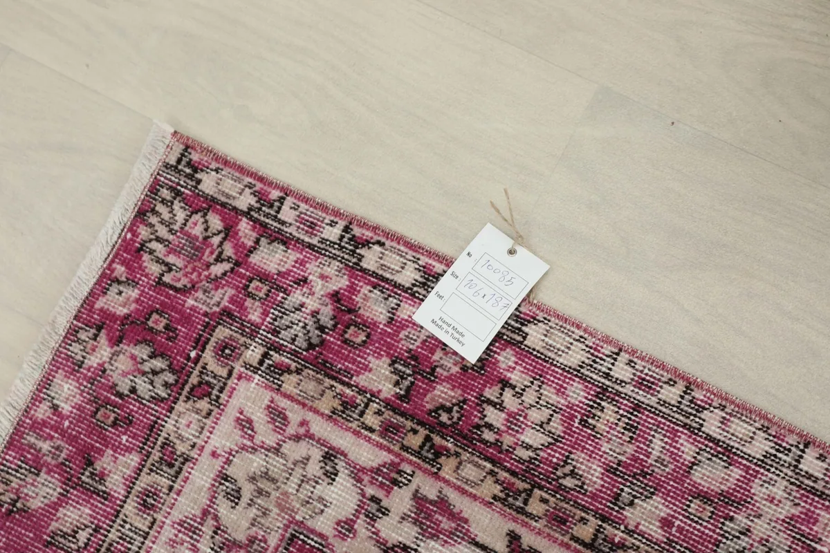 Overhead view of a corner with a tag, highlighting the rug's rose and black patterns