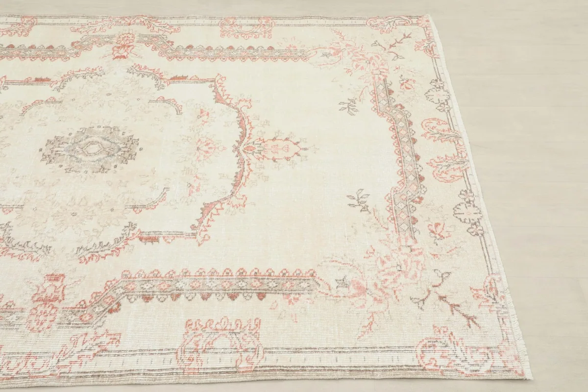 Close-up angled view highlighting the rose and gray medallion pattern on the ivory rug