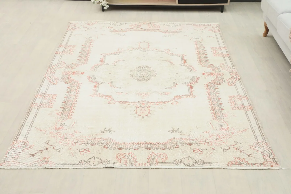 Ivory and rose vintage area rug placed in a room setting, showcasing its size and aesthetic