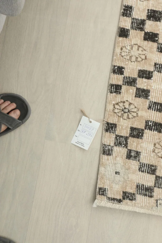 Overhead view of the rug with a size tag, showing the scale next to a person's feet.
