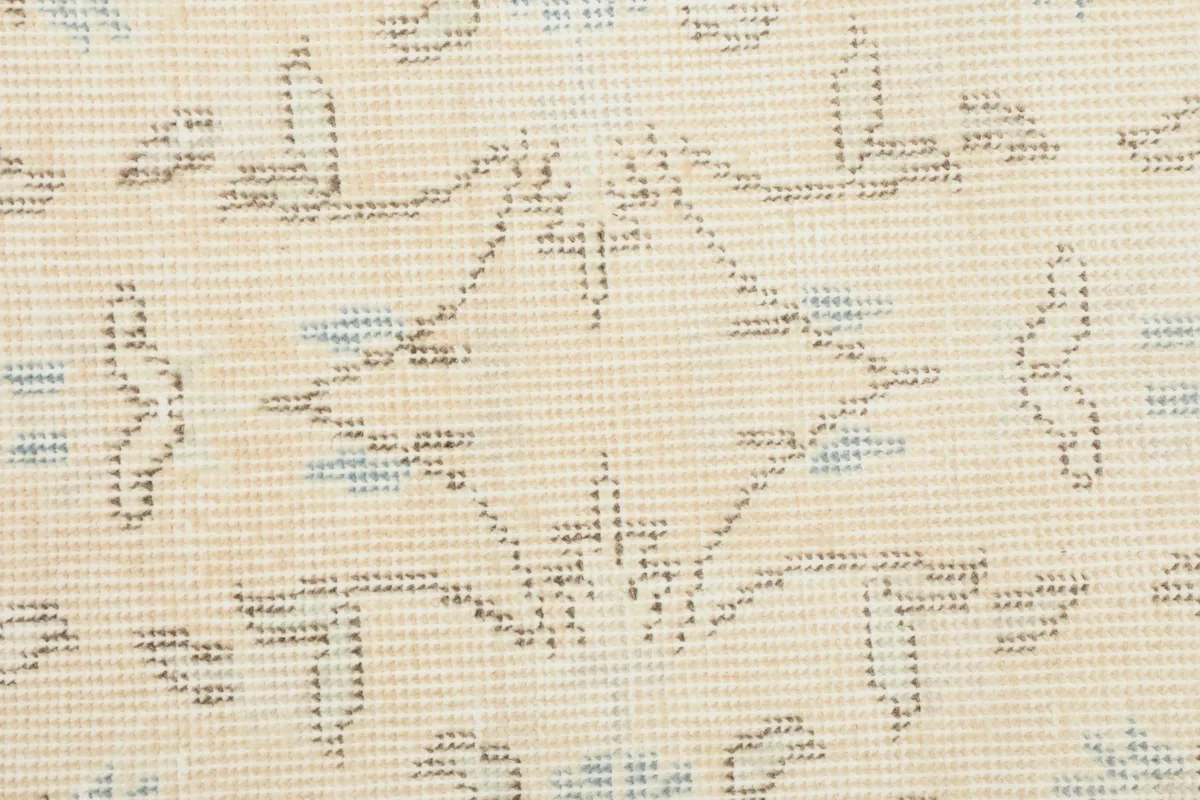 Macro view of the hand-knotted wool pile, showing the texture and faded blue and tan colors.
