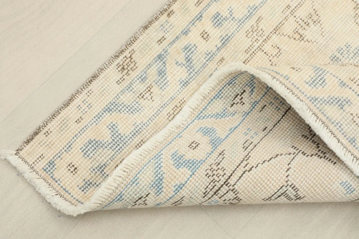 Corner of the rug folded to reveal the cotton foundation and reverse side of the hand-knotting.
