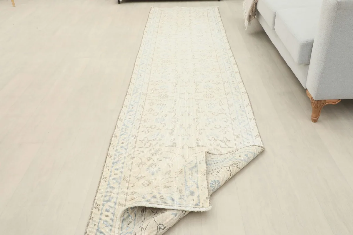 Runner rug partially rolled back in a room setting, showing its flexibility and full length.