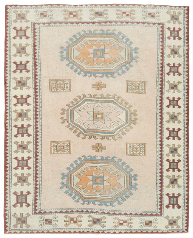 Full overhead view of the beige vintage Anatolian rug with orange and blue geometric medallions.