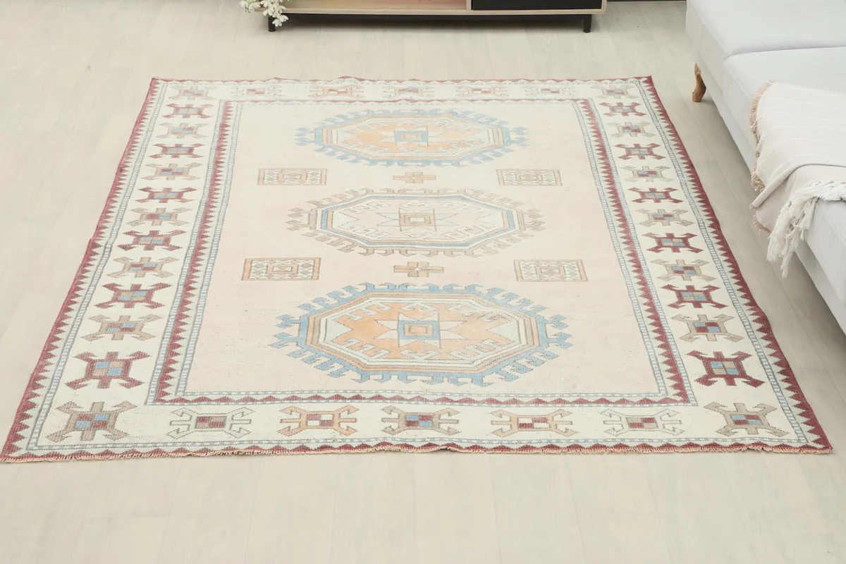 Vintage Anatolian rug placed in a room setting next to a sofa, demonstrating its scale.