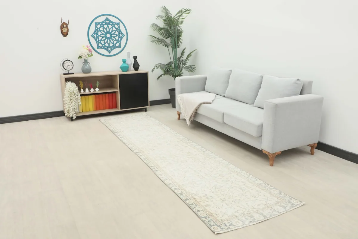 Ivory floral runner rug displayed in a modern room setting with a light gray sofa and minimalist decor.