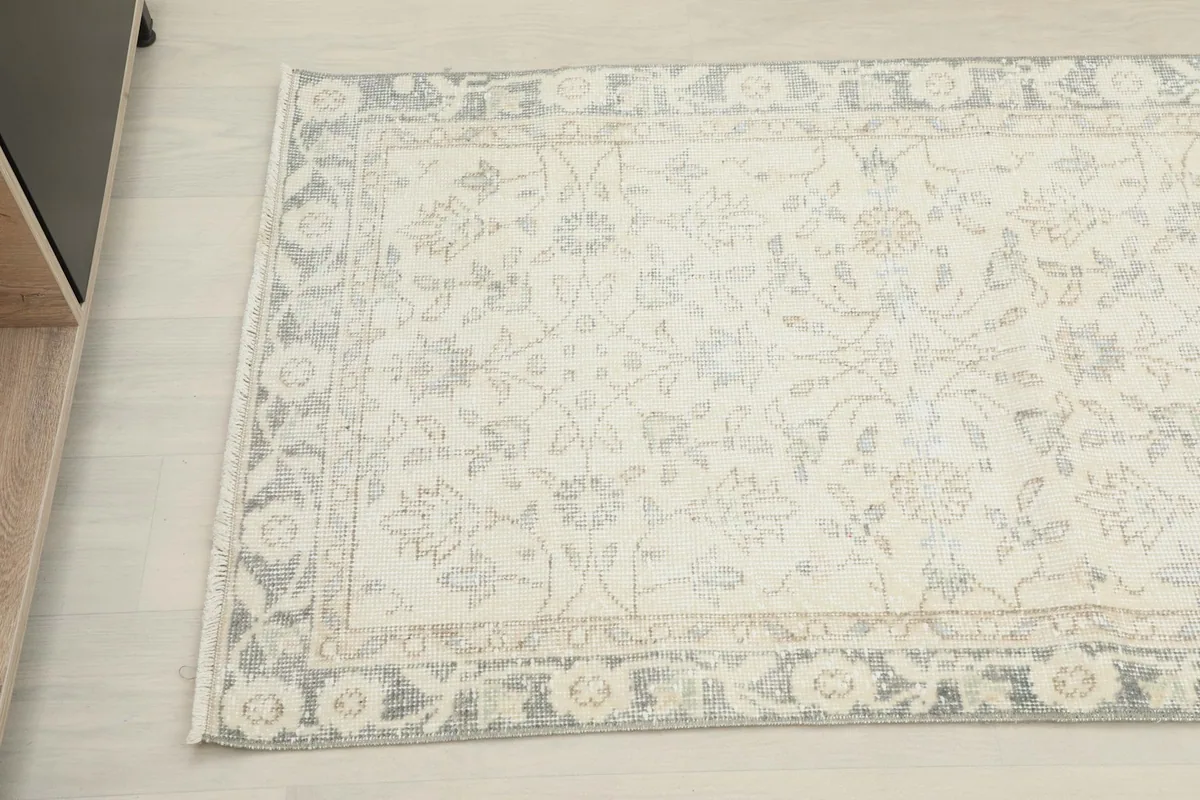 Overhead close-up of the rug's pattern, showing the subtle tan and gray tones within the ivory field.