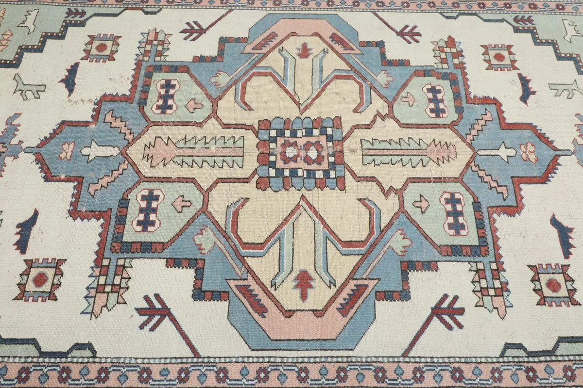 Detailed view of the rug's central medallion with blue, pink, and beige tones