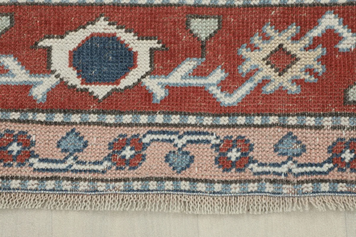 Close-up of the rug's red main border and the delicate rose-colored inner border