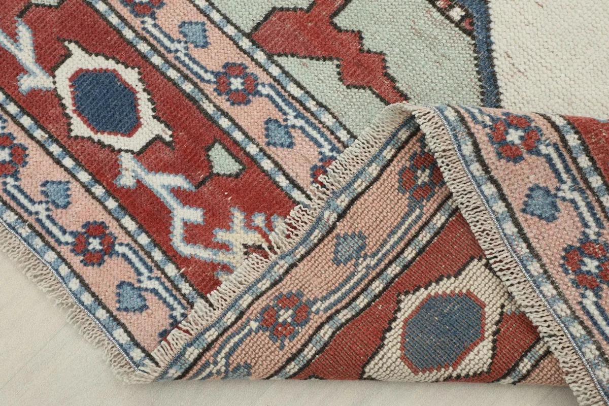 Corner of the rug folded to show the thickness and flexibility of the hand-knotted weave