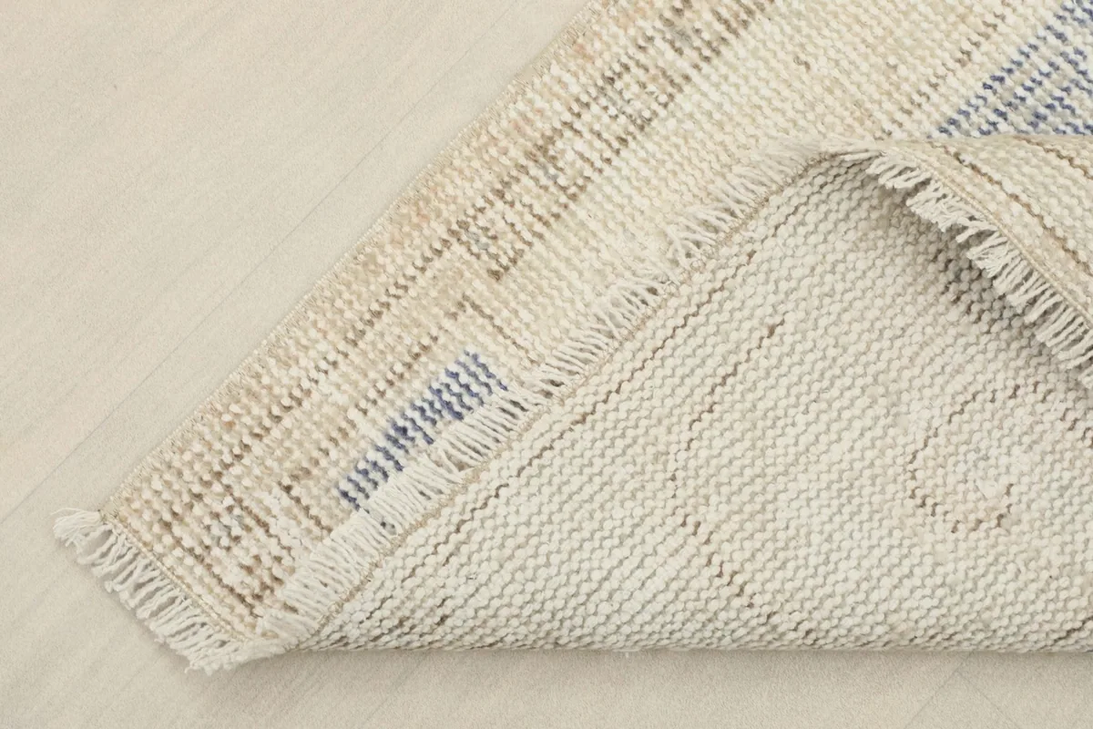 Corner of the rug folded to show the hand-knotted cotton foundation and wool pile
