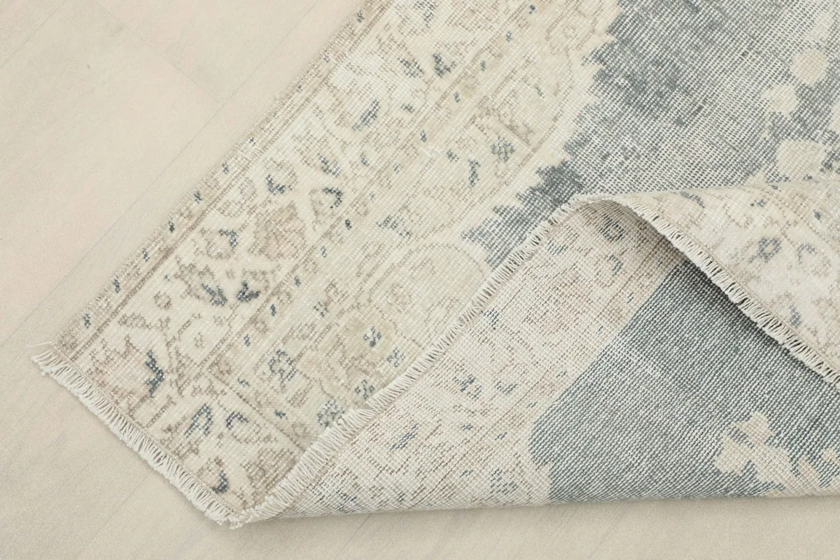 Corner of the rug folded back, showing the cotton foundation and reverse side