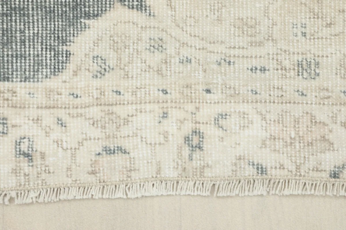 Close-up of the rug's short ivory fringe and border texture