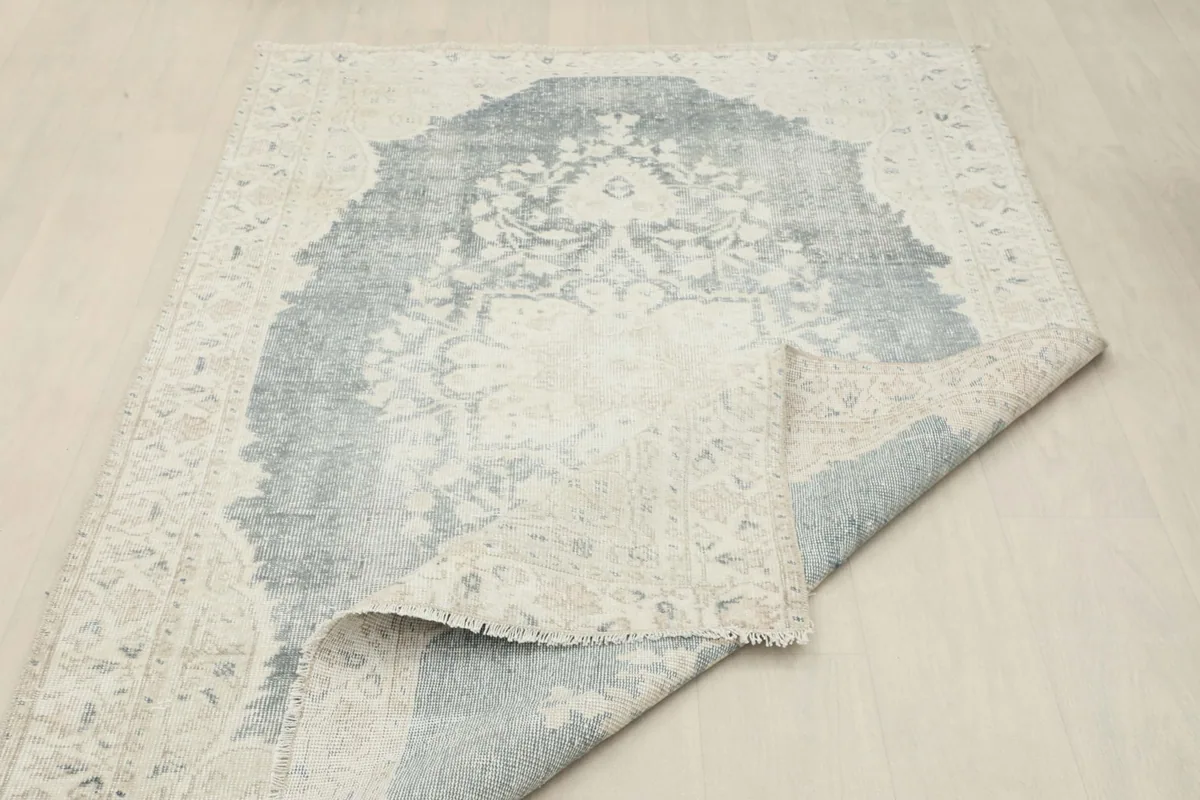 Rug partially folded, revealing the hand-knotted construction and texture