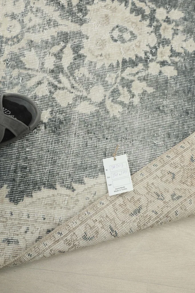 Rug tag detail next to the folded rug, indicating material and origin
