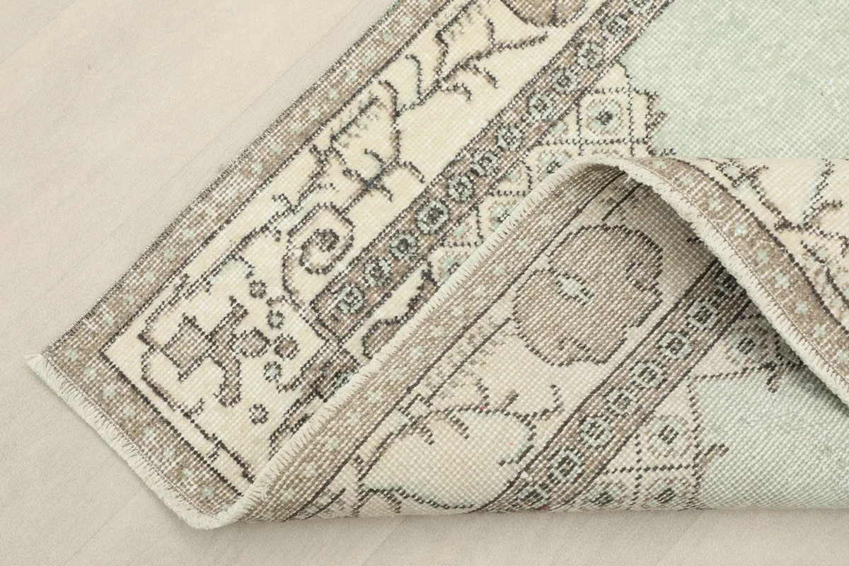Corner of the rug folded back to reveal the cotton foundation and hand-knotted construction