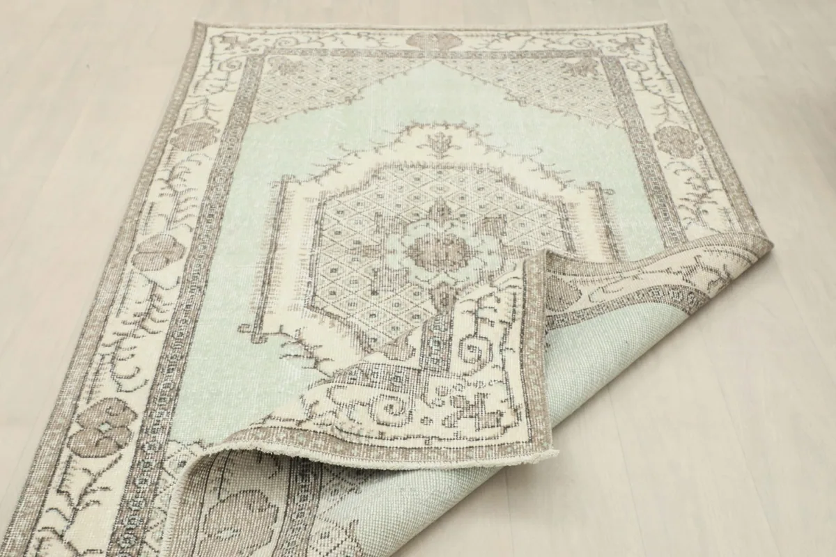Rug partially folded, showing the reverse side and the overall faded appearance