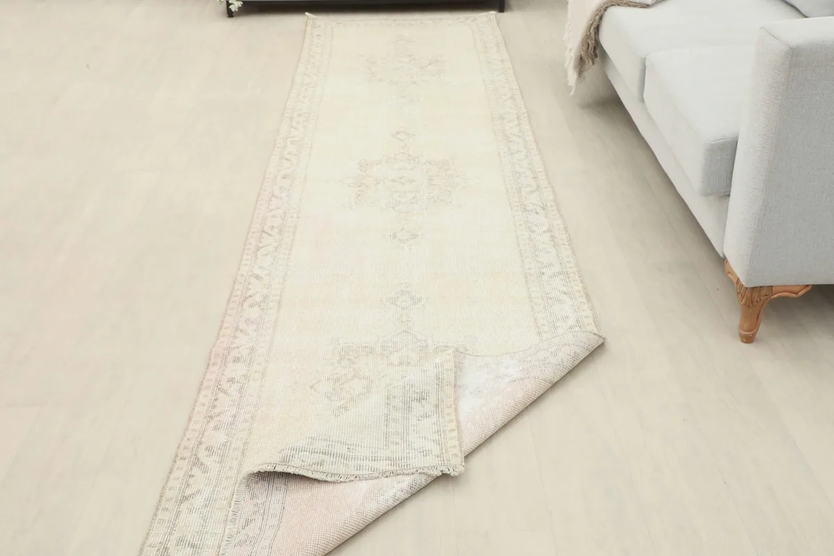 Runner rug with a corner folded back, showing the back of the rug and its foundation