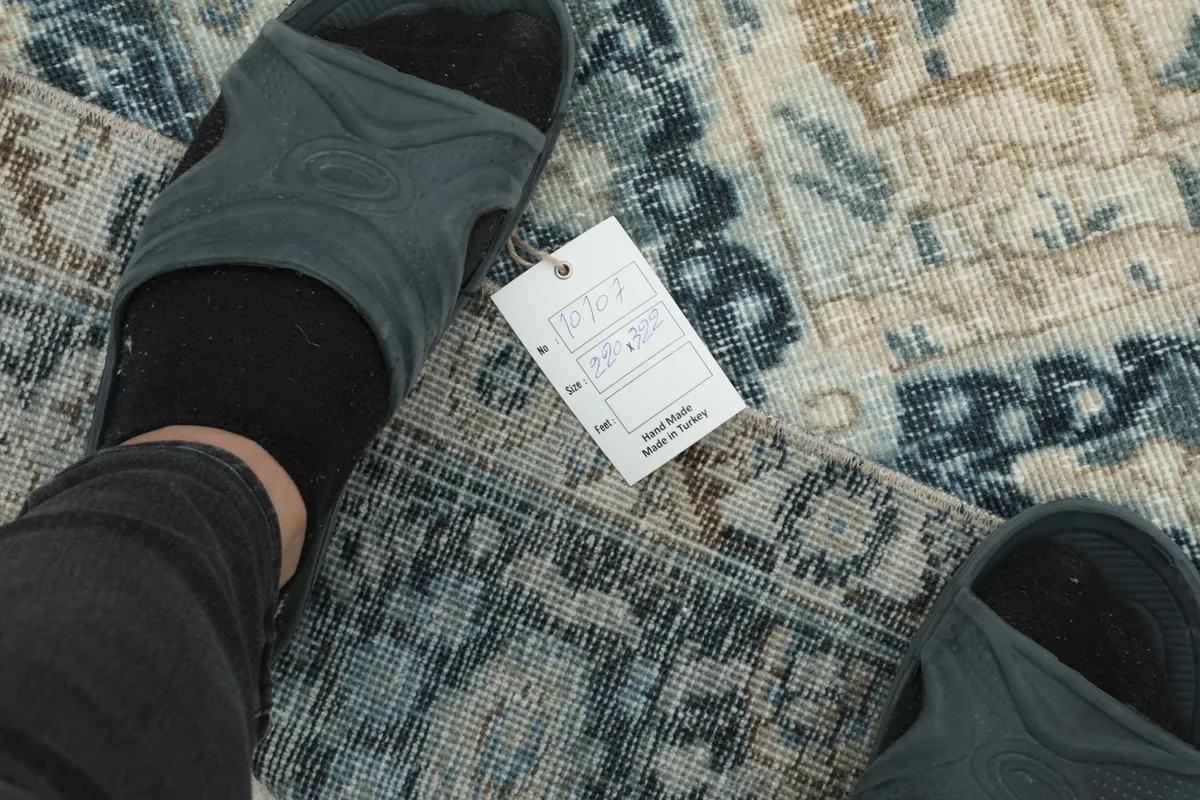 Feet on the rug with a tag, showing the texture and color variations up close