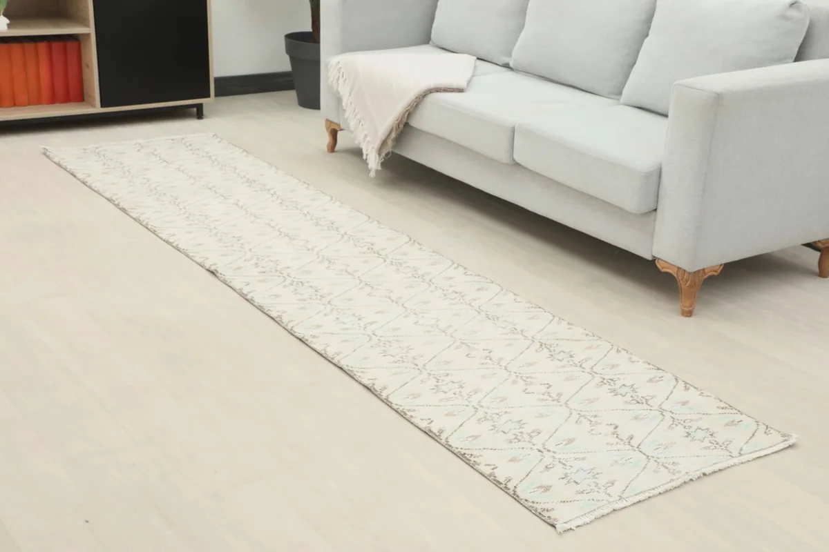 Angled view of the cream runner extending from a light gray sofa in a room setting.