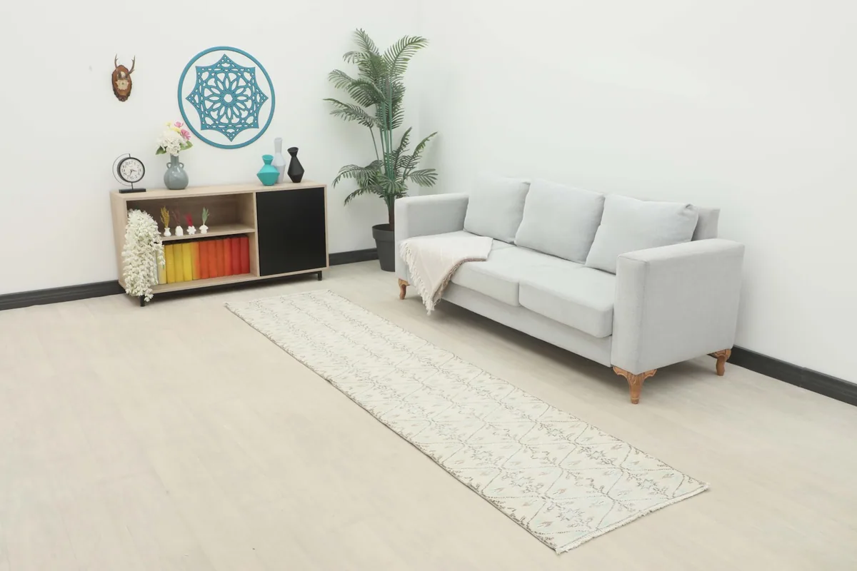 Long view of the cream runner placed in a modern living space with a light gray sofa.