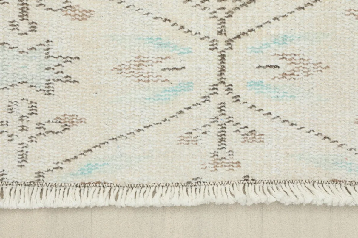 Close-up of the short, neatly finished fringe at one end of the cream runner.