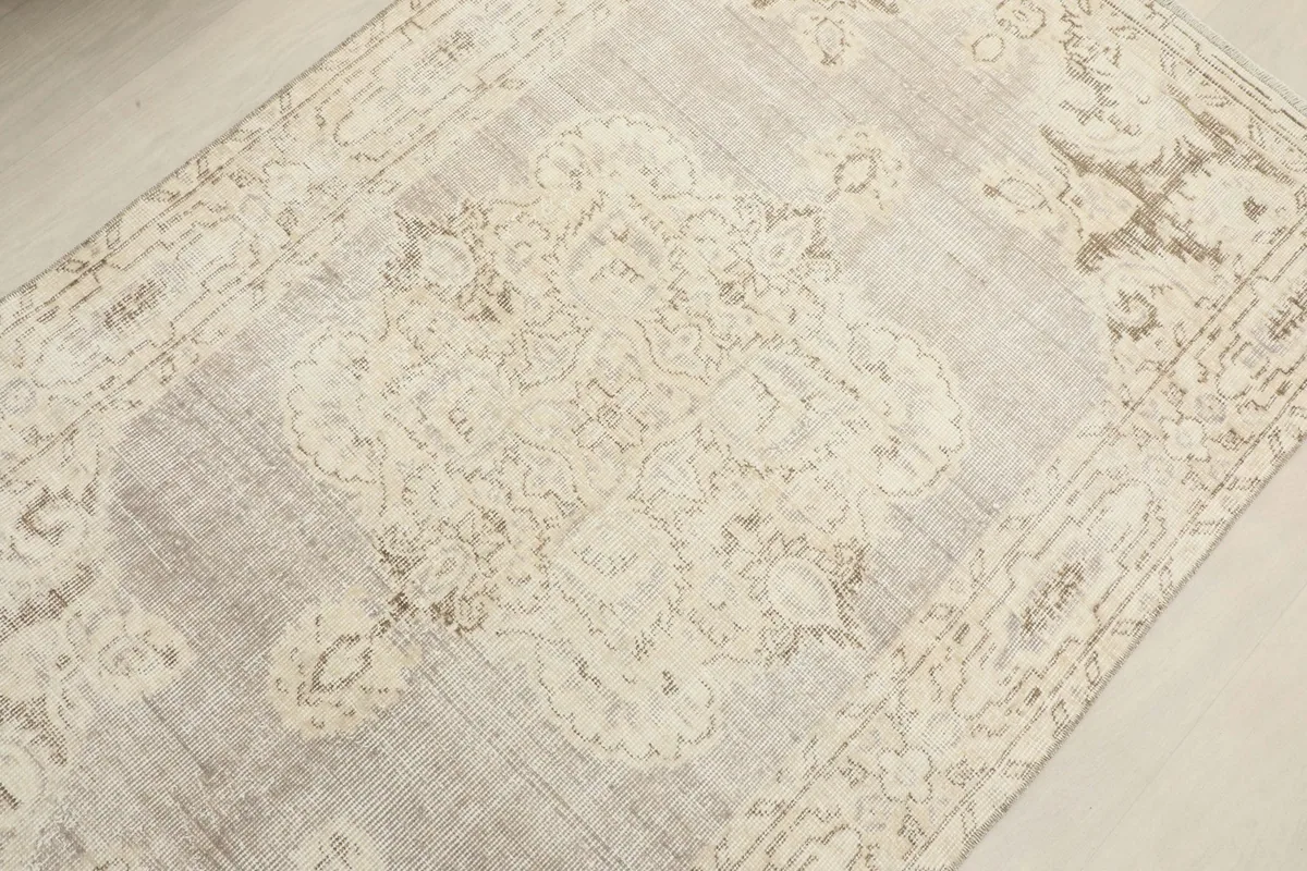 Overhead angle shot of the rug's central medallion and field, revealing the beige and gray tones