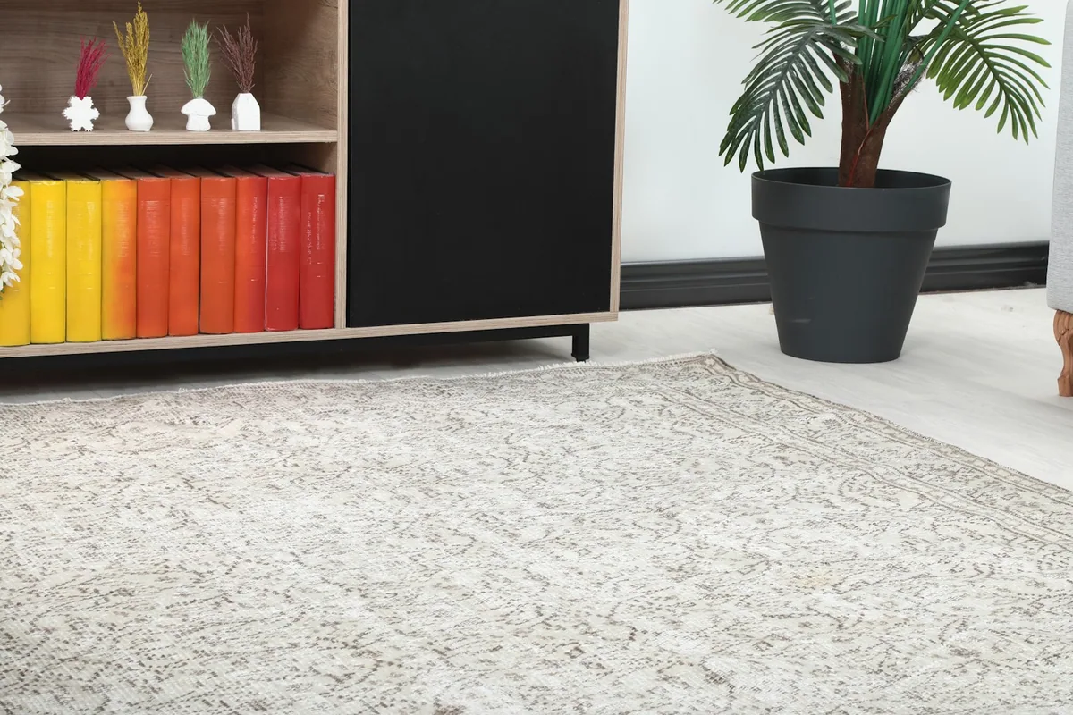 Close-up of the rug's subtle floral pattern and border, showing its texture next to a cabinet