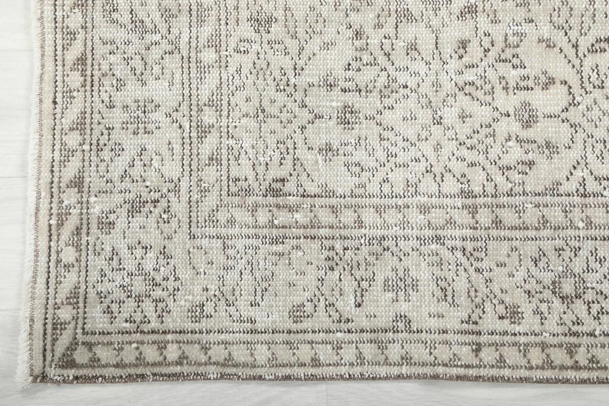 Corner detail of the rug's border, showcasing the geometric and floral designs and natural fringe