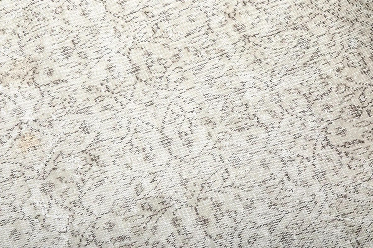 Close-up of the rug's hand-knotted wool pile, revealing the subtle variations in ivory and beige tones