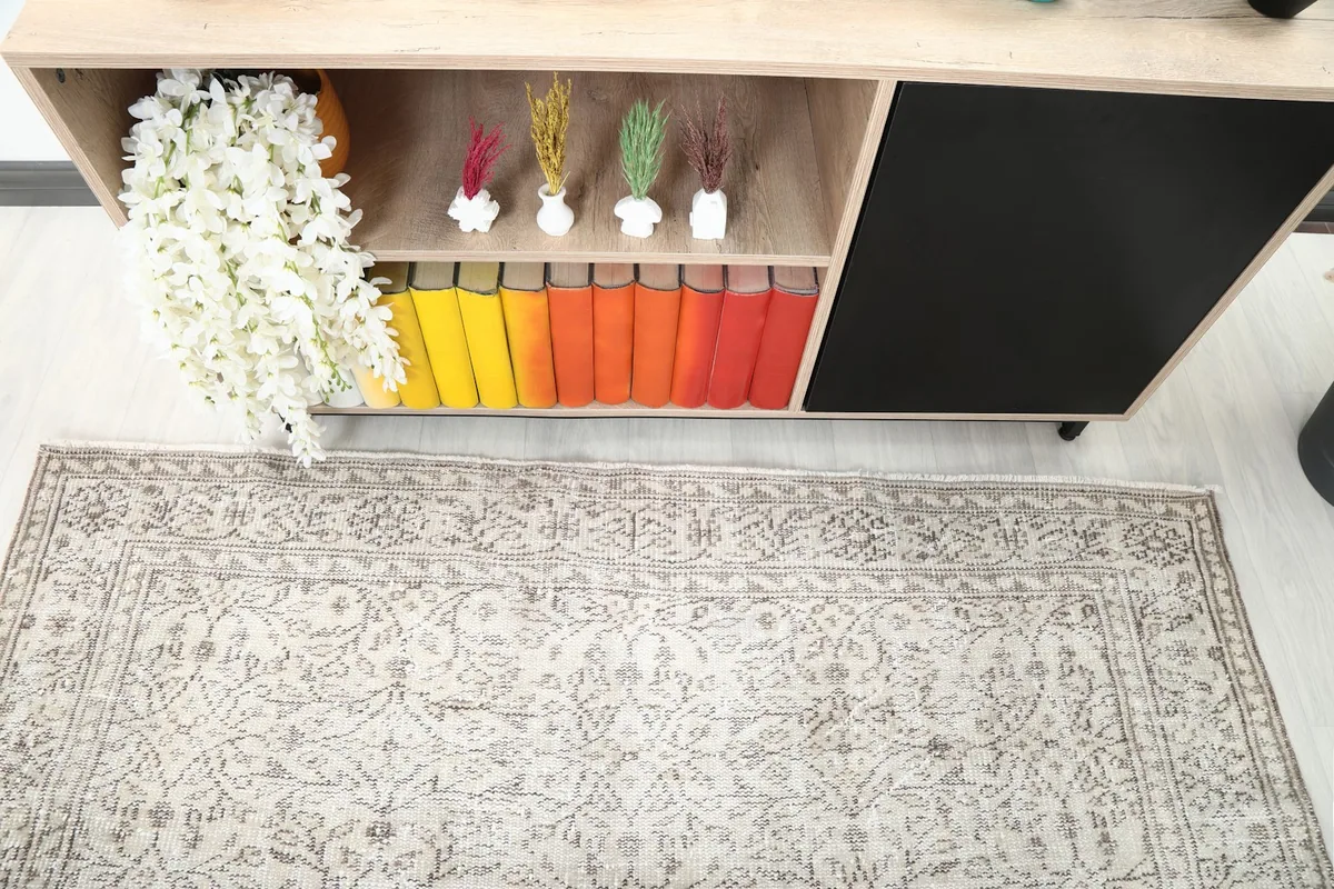 Top-down view of the rug's field and border, showing its intricate patterns near a bookshelf