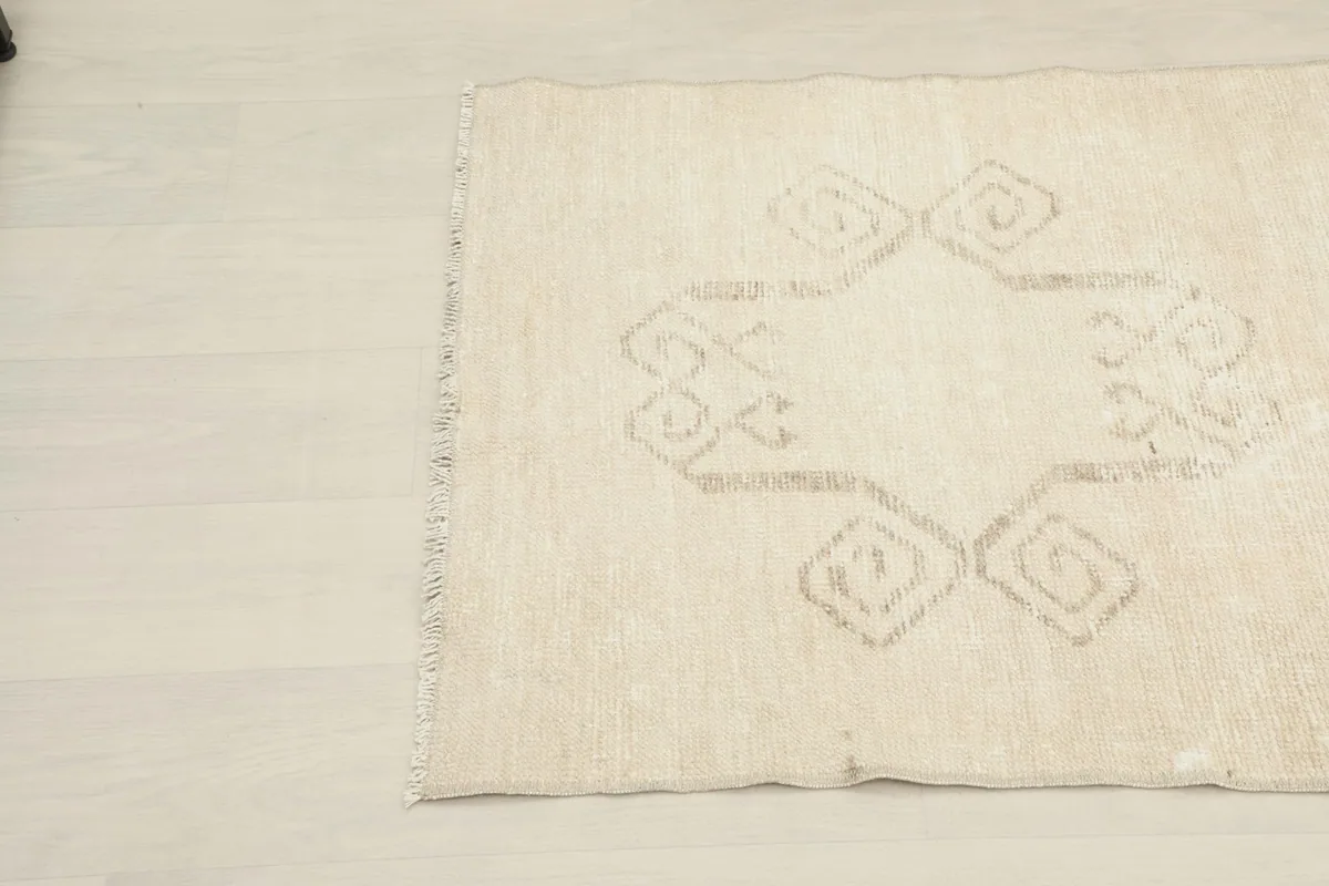 Close-up angled view of the ivory rug's right side with tan geometric motifs