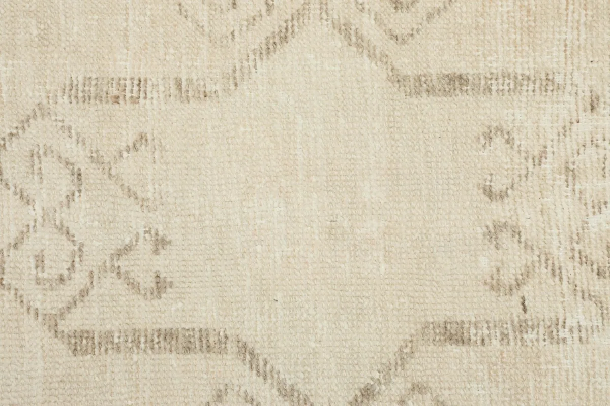 Detailed close-up showing the hand-knotted texture and faded tan geometric design