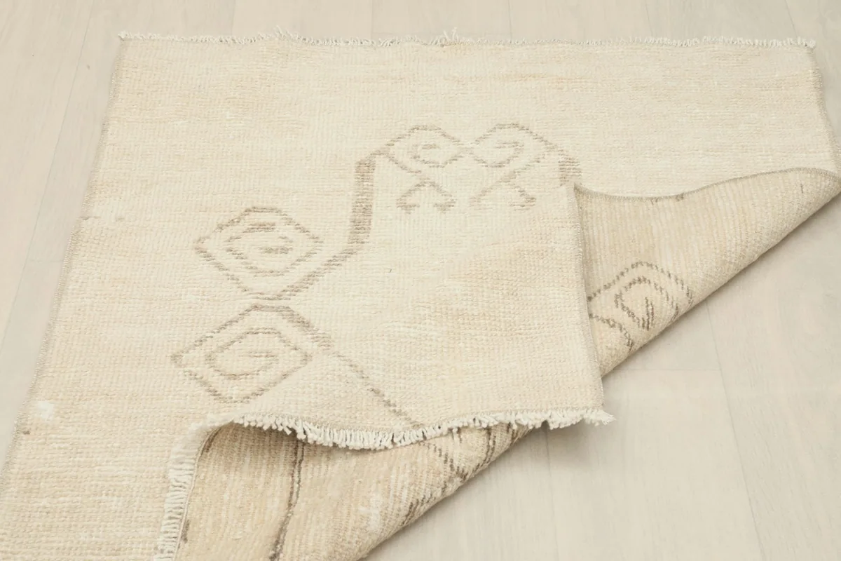 Partial view of the rug's back, showing the cotton foundation and construction