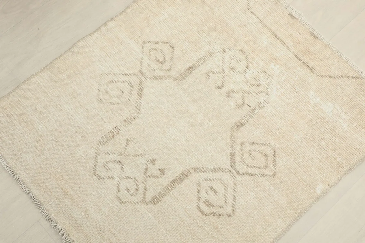 Overhead close-up of the central tan geometric pattern on the ivory wool rug