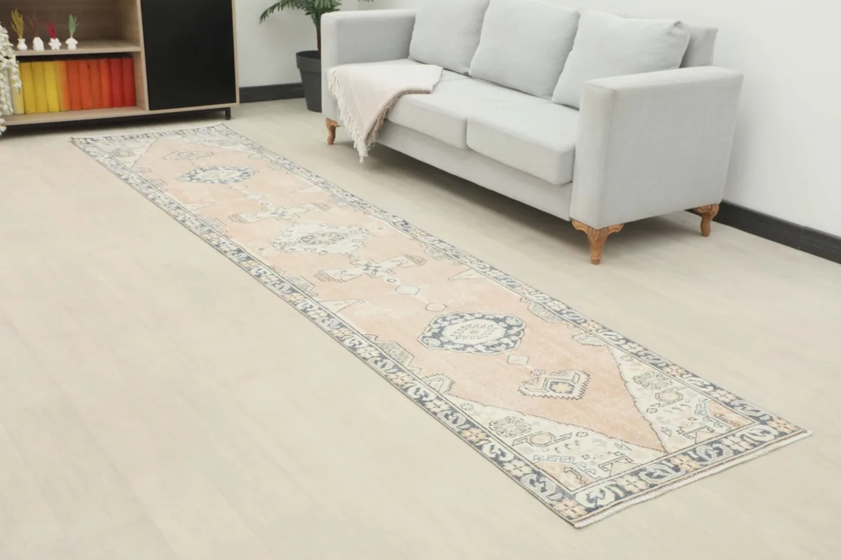 Angled view of the rose tribal runner rug in a room, highlighting its length and placement next to a sofa.
