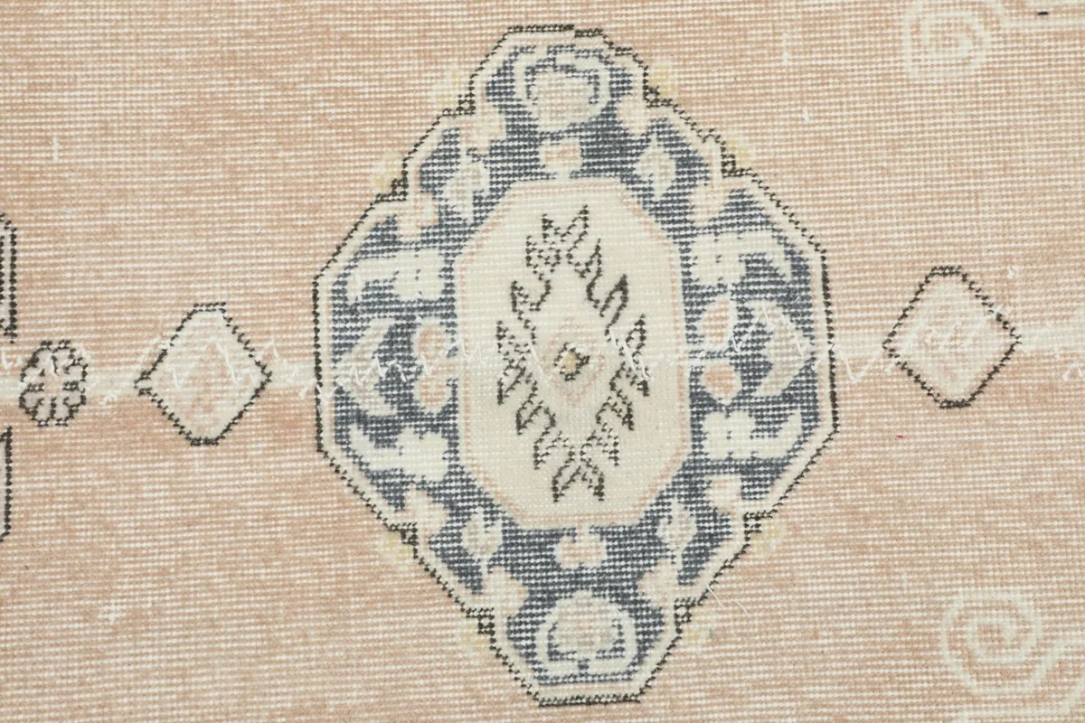 Detailed shot of a prominent navy and ivory medallion motif within the rose field of the runner.