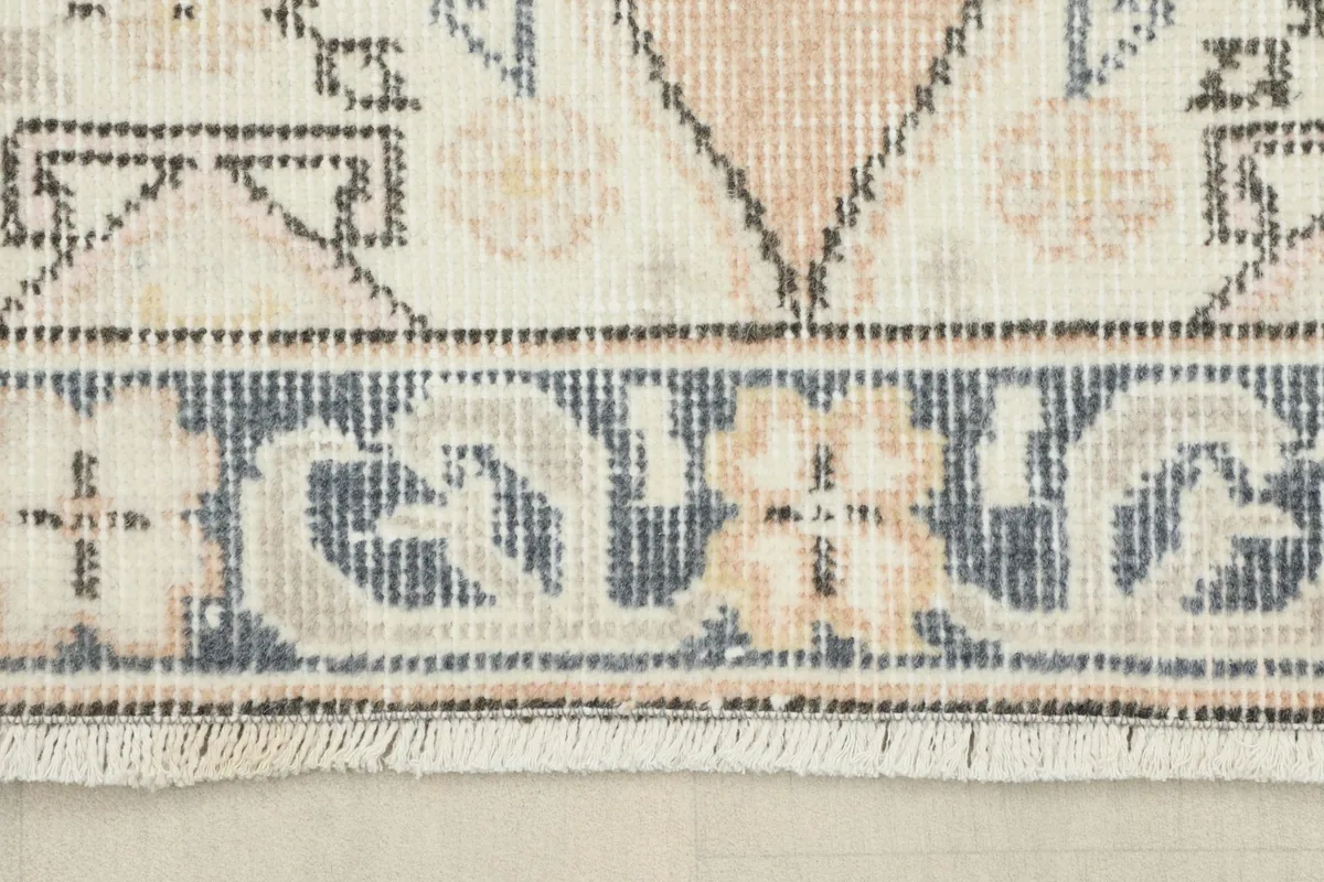 Close-up of the navy and ivory border design with floral-like elements and the short fringe.