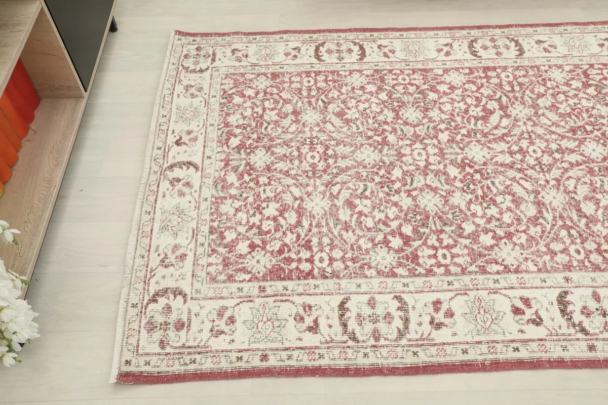 Detailed view of the rug's pattern and border, showing the blend of rose and ivory tones