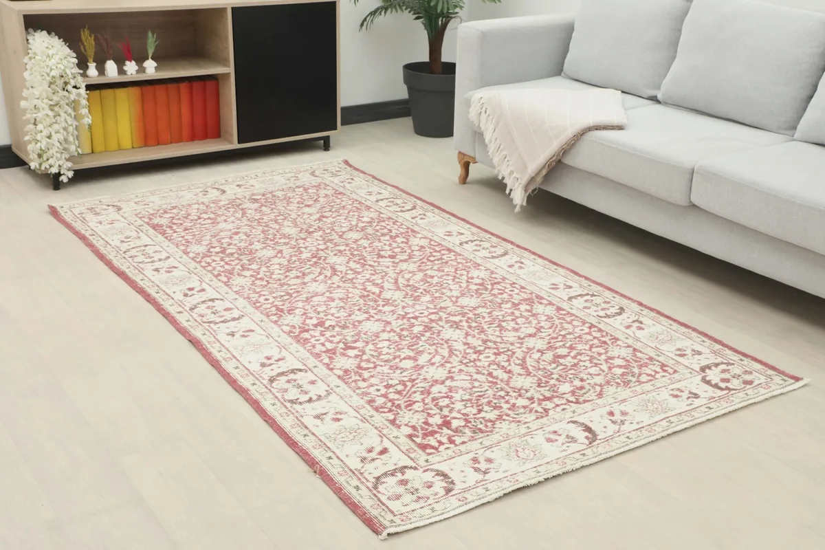Angle view of the rose and ivory floral rug in a room, showing its placement next to a sofa