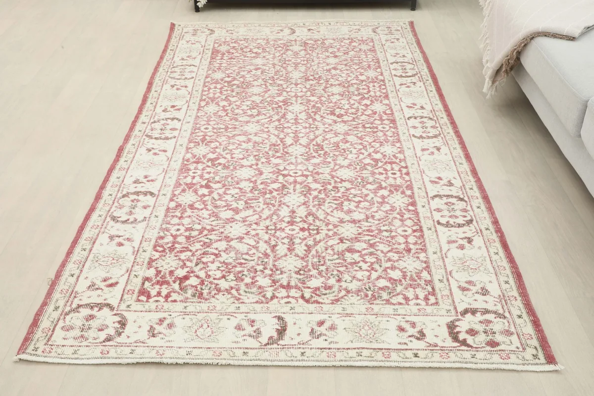 Full view of the rose and ivory vintage rug laid out in a room, offering a complete perspective
