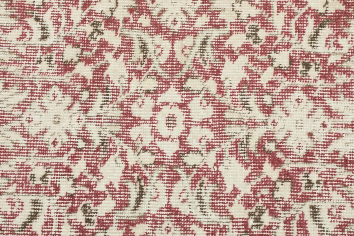 Extreme close-up of the rose and ivory floral pattern, revealing the hand-knotted wool pile