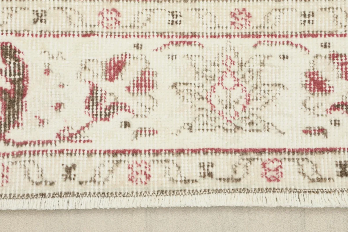 Close-up of the ivory border and short fringes of the vintage hand-knotted rug