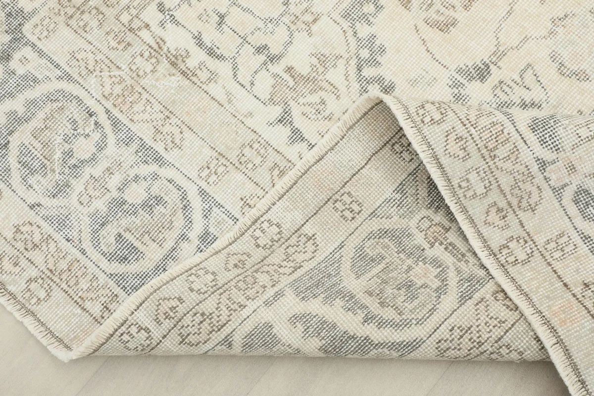 View of the rug with a corner folded back, revealing the cotton foundation and hand-knotted construction