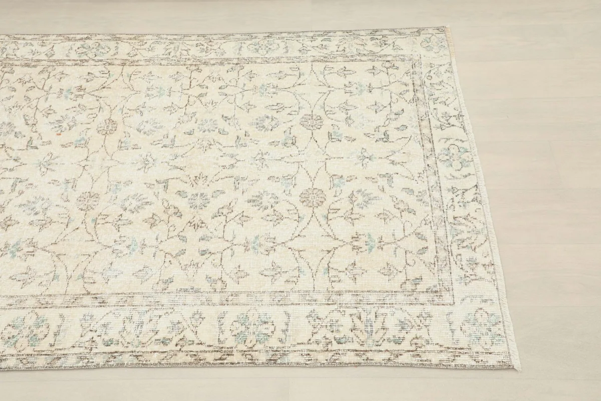 Close-up of the rug's corner showing the subtle ivory and tan floral pattern