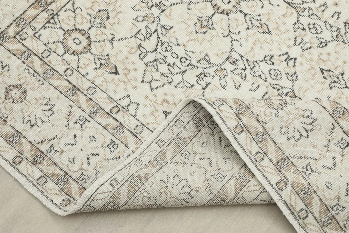 Rug corner folded back, showing the cotton foundation and the reverse side of the hand-knotting.