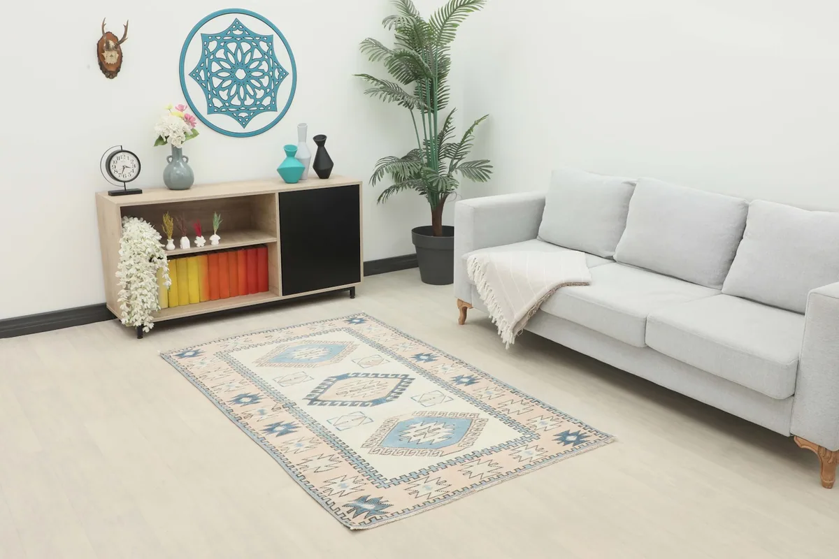 Vintage Anatolian rug placed in a living room setting with a light gray sofa and wooden cabinet.