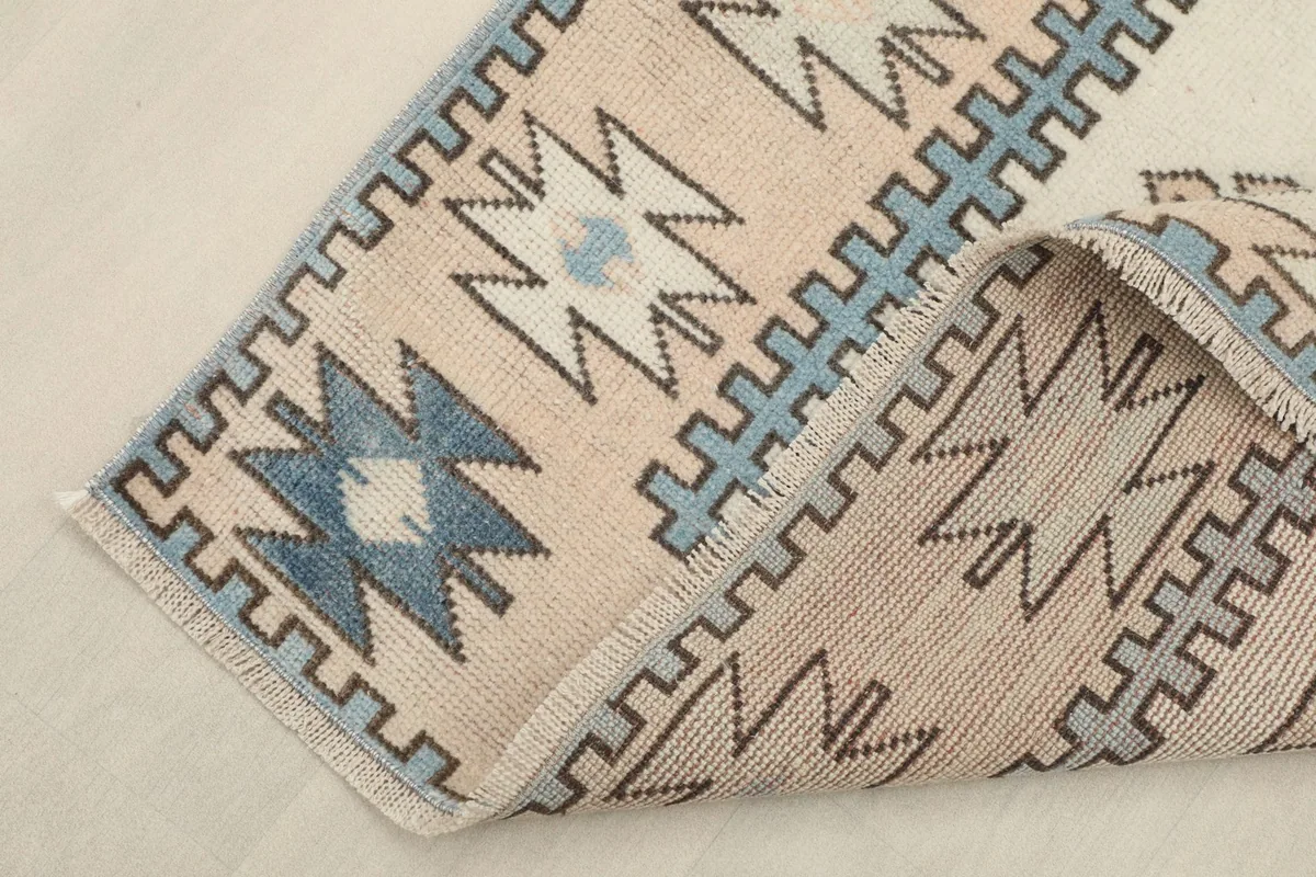 Corner of the rug folded back, showing the consistent pattern and the reverse side of the hand-knotted wool.