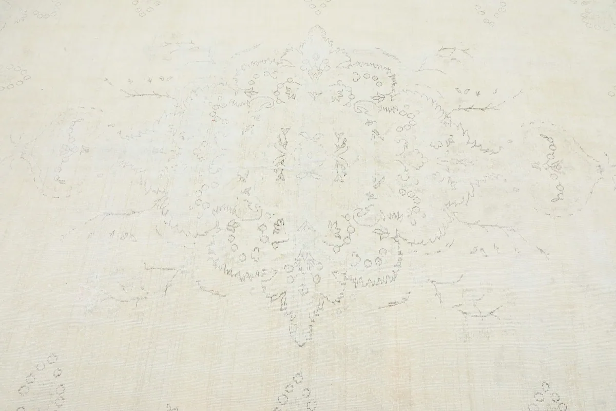 Close-up detail of the central faded floral medallion pattern on the cream rug.