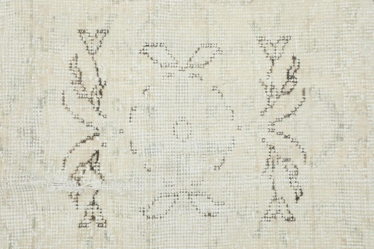 Close-up detail of a specific faded floral motif within the rug's design.